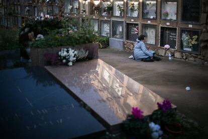 Una mujer descansa delante de un nicho de un familiar, en el cementerio de Montjüic (Barcelona).