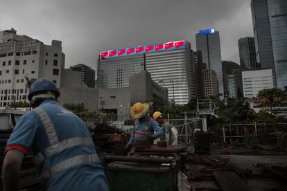 Los trabajadores refuerzan un patio de metal, mientras, a lo lejos se ve un edificio con banderas nacionales chinas en Hong Kong, el 2 de septiembre.