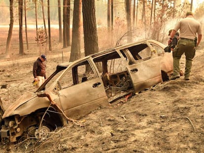 Policiais inspecionam neste domingo um automóvel destruído pelo fogo em Concow (Califórnia).