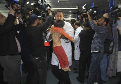 Un médico palestino lleva en brazos el cuerpo sin vida de un niño fallecido en los ataques aéreos de Israel en Gaza durante la visita del primer ministro egipcio Hisham Qandil y el primer ministro de Hamás, Ismail Haniye, (no fotografiados)