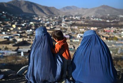 Dos mujeres afganas con burka sentadas en un cementerio con vistas a las afueras de Kabul.