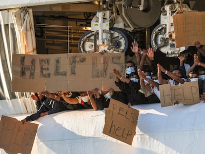 Migrantes retenidos en el muelle de Catania (Italia) muestran pancartas pidiendo ayuda, este lunes.