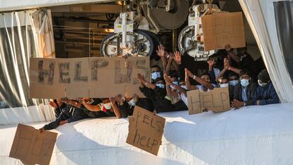 Migrantes retenidos en el muelle de Catania (Italia) muestran pancartas pidiendo ayuda, este lunes.