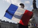 A demonstrator holds a French flag with the slogan "Freedom of Speech" during a demonstration Sunday Oct. 18, 2020 in Paris. Demonstrations around France have been called in support of freedom of speech and to pay tribute to a French history teacher who was beheaded near Paris after discussing caricatures of Islam's Prophet Muhammad with his class. Samuel Paty was beheaded on Friday by a 18-year-old Moscow-born Chechen refugee who was shot dead by police. (AP Photo/Michel Euler)