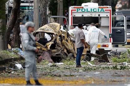 Integrantes de la Dijín inspeccionan un vehículo afectado tras una explosión en Cali, el 21 de agosto.
