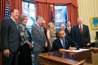 Barack Obama firma documentos en el Despacho Oval.