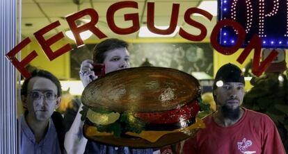 Varios ciudadanos, entre ellos el enviado especial de EL PAÍS en Ferguson, observan los disturbios desde un restaurante.