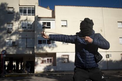 Un manifestante encapuchado ataca a la policía con un tirachinas.