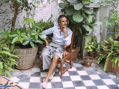 El interiorista Lorenzo Castillo posa para ICON Design en el patio de su casa de Madrid, sentado en una silla inglesa de laca del siglo XVIII con un pantalón de Gucci. |