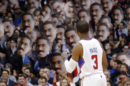 Chris Paul celebra una canasta con los seguidores de los Clippers, que llevan caretas con su cara.