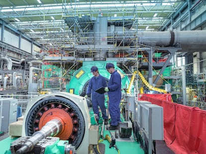 Dos ingenieros inspeccionan la maquinaria del generador en una central nuclear durante una interrupción.