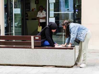 Dos mujeres rellenan un impreso delante de la única oficina de Correos de Melilla, el jueves.