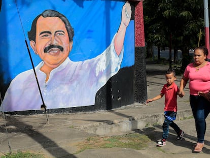 Una mujer pasea con sus hijos delante de un mural de Daniel Ortega, este lunes en Managua.