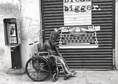 Un indigente en silla de ruedas mira al fotógrafo en una calle de Skid Row.