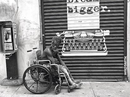Un indigente en silla de ruedas mira al fotógrafo en una calle de Skid Row.