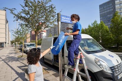 Dos operarias del Ayuntamiento de Vitoria sustituyen la placa con el nombre de Avenida de Juan Carlos I.