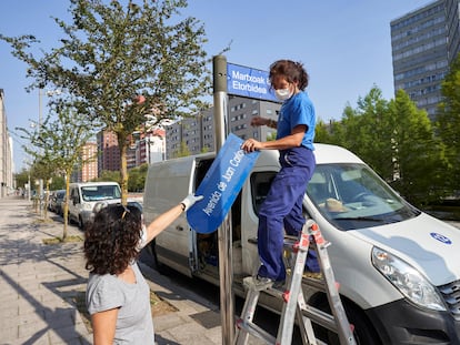 Dos operarias del Ayuntamiento de Vitoria sustituyen la placa con el nombre de Avenida de Juan Carlos I.