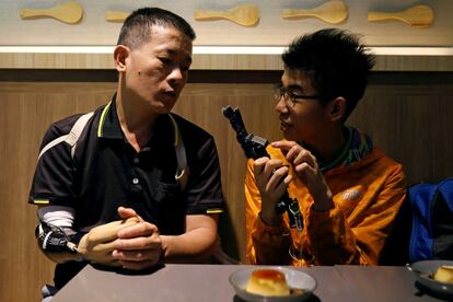 Engineer Chang Hsien-Liang (L), 46, shows a friend prosthetic hand, which he designed and built, in Taoyuan, Taiwan, April 28, 2017. REUTERS/Tyrone Siu         SEARCH "PROSTHETIC 3D" FOR THIS STORY. SEARCH "WIDER IMAGE" FOR ALL STORIES.