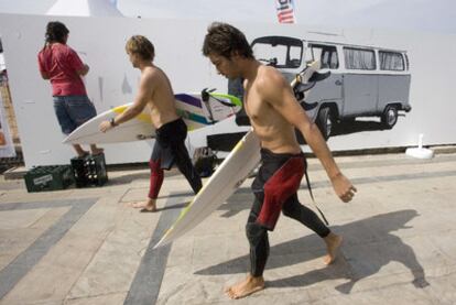 Dos surfistas pasan junto un mural que pinta un joven, ayer en la salida de la playa de Zarautz.