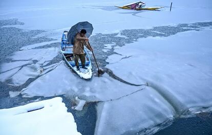 Un hombre sobre un bote rompe el hielo del lago Dal durante una nevada en Srinagar (India), el 13 de enero.