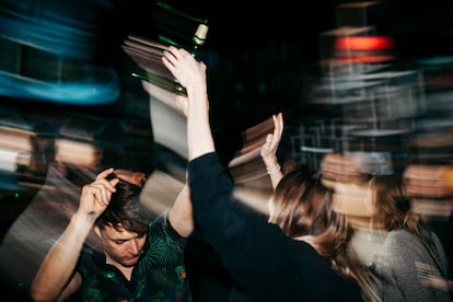 An energetic scene with people on the dancefloor dancing and drinking at a colourful, open air nightclub