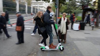 Dos jóvenes montan en un patinete eléctrico de alquiler Lime.