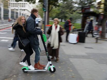 Dos jóvenes montan en un patinete eléctrico de alquiler Lime.