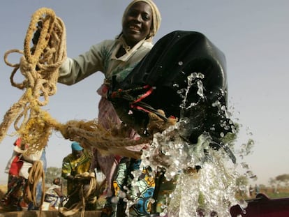Una agricultora toma agua de un pozo para regar los cultivos, en Níger.