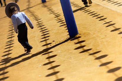 Un niño vestido de corto, juega con las sombras de los farolillos. 