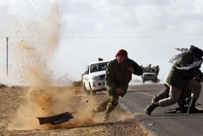 Milicianos rebeldes esquivan las balas de las tropas de Gadafi durante los enfrentamientos de ayer cerca de Bin Yauad.