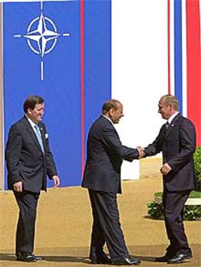 Silvio Berlusconi saluda a Vladimir Putin en presencia de George Robertson.