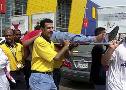 Empleados de la tienda Ikea de Jeddá, en Arabia Saudí, llevan a un hombre herido ayer en la apertura del local.