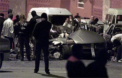 Policías vascos revisan los restos del coche en que iban los etarras fallecidos anoche en Bilbao.