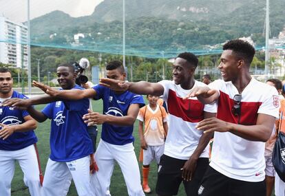 Os jogadores ingleses Danny Welbeck e Daniel Sturridge (ambbos de branco) dançam axé com moradores da favela da Rocinha, no Rio.