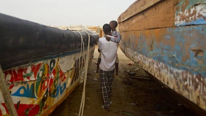 Un padre pasea con su hijo en brazos entre los cayucos de una playa de Nuakchot, en Mauritania.