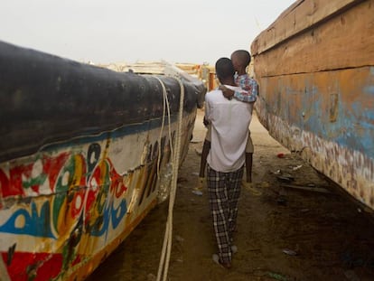 Un padre pasea con su hijo en brazos entre los cayucos de una playa de Nuakchot, en Mauritania.