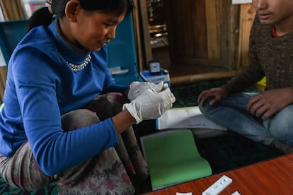 Htan Pi, una voluntaria de salud comunitaria de la ONG Medical Action Myanmar (MAM), toma una muestra de sangre de un paciente para detectar si tiene malaria. Lo hace en su casa en el pueblo de Satpalaw Shaung, en el municipio de Lahe, al noroeste de Myanmar. Las tribus naga de Myanmar permanecen en gran medida aisladas del resto del país en un área todavía subdesarrollada. Las filas de pacientes esperan la llegada de las clínicas móviles mensuales, administradas por Medical Action Myanmar que, a menudo, funcionan hasta altas horas de la noche a la luz del fuego.