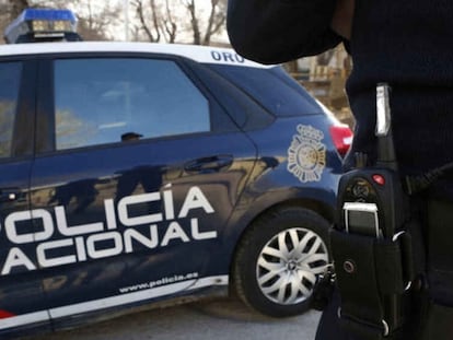 Un agente junto a un coche patrulla de la Policía Nacional.