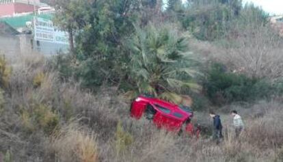 Dos hombres observan el vehículo accidentado.