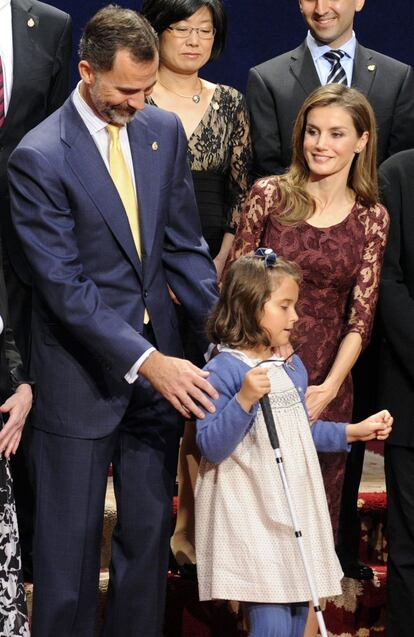 Los Príncipes de Asturias junto a la niña, Liv Parlee Cantin, que ha acudido al Hotel de la Reconquista de Oviedo para la entrega de insignias, ya que la ONCE ha merecido este año el Premio Príncipe de Asturias de la Concordia y ella forma parte de los 7.600 niños ciegos a los que esta entidad presta ayuda.