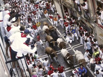 Los mozos corren, en el inicio de la calle Estafeta, junto a los toros.