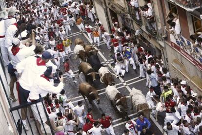 Los mozos corren, en el inicio de la calle Estafeta, junto a los toros.