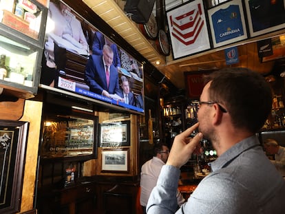 Un hombre en una taberna de Dublín viendo en la televisión al ministro de Finanzas, Michael McGrath.