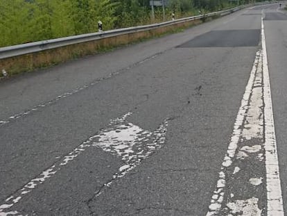 Tramo de carretera con marcas viales deterioradas, firme bacheado, con grietas longitudinales y roderas.