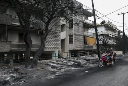 Dos jóvenes pasan por una calle afectada de Mati afectada por los incendios.