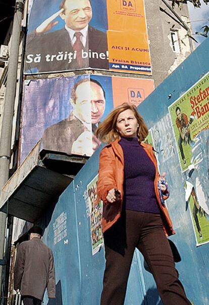 Una mujer pasa bajo dos carteles del alcalde de Bucarest, Traian Basescu.