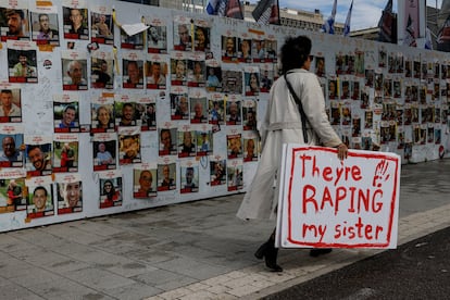 Una manifestante caminaba el día 29 en Tel Aviv junto a un mural con imágenes de rehenes secuestrados por Hamás en su ataque del 7 de octubre. Su cartel dice: "Están violando a mi hermana".