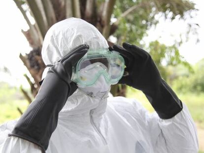 Um enfermeiro se protege para transportar uma vítima do ebola na Libéria.