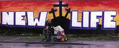 Una familia norirlandesa pasa ante una pintada a favor de la paz en el centro de Belfast.