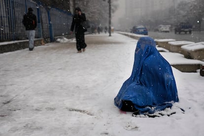 Una afgana cubierta por un burka pide limosna sentada en la nieve en una calle de Kabul el 6 de febrero.